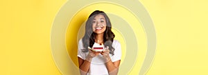 Portrait of beautiful african-american girl celebrating birthday, smiling and looking happy and holding b-day cake with