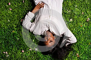 Portrait of beautiful african american woman laying on green grass in park