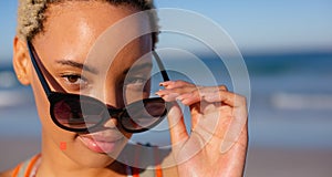 Beautiful woman looking over sunglasses on beach in the sunshine