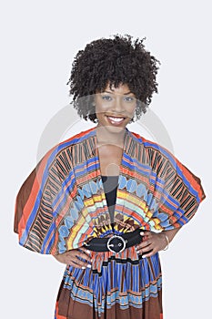 Portrait of beautiful African American woman in traditional wear standing over gray background