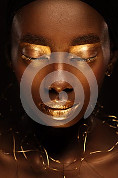 Portrait of beautiful african woman with creative gold makeâ€“up and jewelry