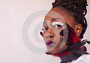 Portrait of a beautiful African woman. Studio with white background. Make up with lashes made of feathers. Fashion style