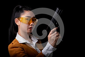 Portrait beautiful asea woman wearing a yellow suit one hand holding pistol gun at the black background