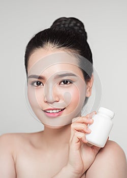 Portrait beautiful asia woman showing product with white plastic pills bottle in hand. Healthy beauty concept