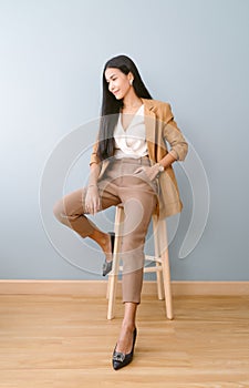 Portrait of beautiful Asian businesswoman sitting on chair and looking away posing standing isolated green pastel background. Full