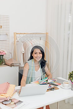 Portrait of beautiful Asian fashion designer sitting at office/workshop