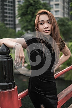 Portrait of beautiful asian girl in casual black dress standing in the park