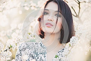 Portrait of beautiful Asian girl among cherry sakura blossoms