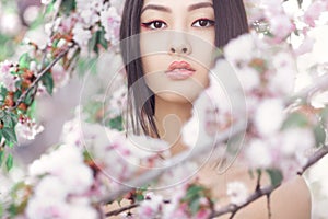 Portrait of a beautiful asian girl outdoors against spring blossom tree.