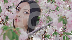 Portrait of a beautiful asian girl outdoors against spring blossom tree.