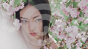 Portrait of a beautiful asian girl outdoors against spring blossom tree.