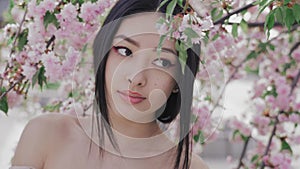 Portrait of a beautiful asian girl outdoors against spring blossom tree.