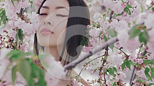 Portrait of a beautiful asian girl outdoors against spring blossom tree.