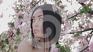 Portrait of a beautiful asian girl outdoors against spring blossom tree.