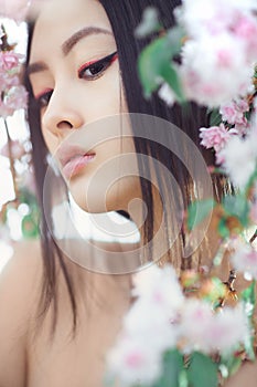 Portrait of a beautiful asian girl outdoors against spring blossom tree.