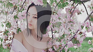 Portrait of a beautiful asian girl outdoors against spring blossom tree. Backstage