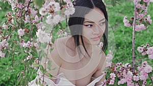 Portrait of a beautiful asian girl outdoors against spring blossom tree. Backstage