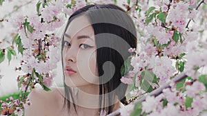 Portrait of a beautiful asian girl outdoors against spring blossom tree. Backstage