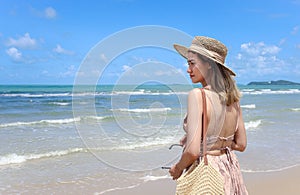 Portrait of beautiful Asian woman with big hat and sunglasses enjoy spending time on tropical sand beach blue sea, happy smiling