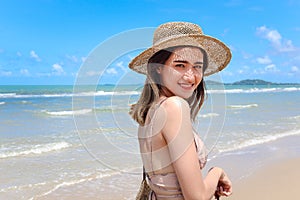 Portrait of beautiful Asian woman with big hat and sunglasses enjoy spending time on tropical sand beach blue sea, happy smiling