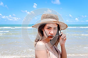 Portrait of beautiful Asian woman with big hat and sunglasses enjoy spending time on tropical sand beach blue sea, happy smiling