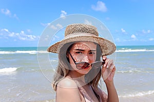 Portrait of beautiful Asian woman with big hat and sunglasses enjoy spending time on tropical sand beach blue sea, happy smiling