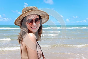 Portrait of beautiful Asian woman with big hat and sunglasses enjoy spending time on tropical sand beach blue sea, happy smiling