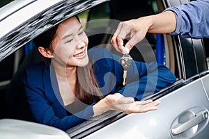 Portrait of a beautiful Asian woman getting a new car, smiling, happy