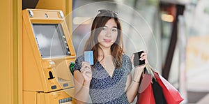 Portrait of beautiful asian woman holding credit card after withdrawing the cash from ATM machine
