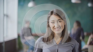 Portrait of beautiful Asian woman in modern office. Young successful businesswoman looking at camera, smiling.