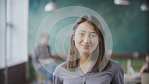 Portrait of beautiful Asian woman in modern office. Young successful businesswoman looking at camera, smiling.