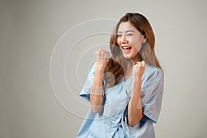 Portrait of a beautiful Asian woman in patient gown raised her arms to cheer up and feel lucky after annual check up with good