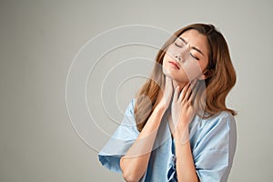 Portrait of a beautiful Asian woman in patient gown raised her hands and touch her neck feeling like pain from office syndrome on