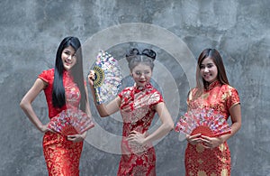 Portrait of a beautiful Asian woman wearing a red cheongsam holding a wooden fan in hand