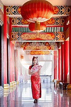 Portrait beautiful Asian young woman wearing red traditional Chinese cheongsam decoration and holding a Chinese Fanning in Chinese