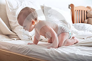 Portrait of beautiful baby 11 months old in diaper on bed close-up. Skincare, healthcare concept for children