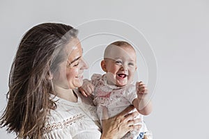 Portrait of a beautiful baby girl and her mother at home. Family concept indoors. Daytime and lifestyle