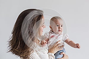 Portrait of a beautiful baby girl and her mother at home. Family concept indoors. Daytime and lifestyle