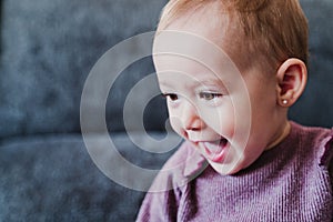 portrait of beautiful baby girl smiling at home sitting on the sofa