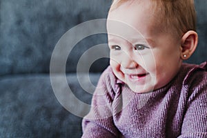 portrait of beautiful baby girl smiling at home sitting on the sofa