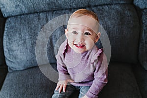 portrait of beautiful baby girl smiling at home sitting on the sofa