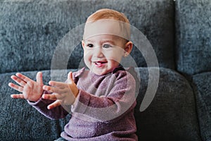 portrait of beautiful baby girl smiling at home sitting on the sofa