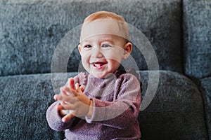 portrait of beautiful baby girl smiling at home sitting on the sofa