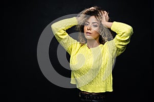 Portrait of a beautiful black female fashion model with curly hair over black background.