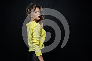 Portrait of a beautiful black female fashion model with curly hair over black background.
