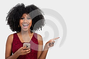 Portrait of a beautiful black girl holding a cell phone and with her other hand pointing to the right side