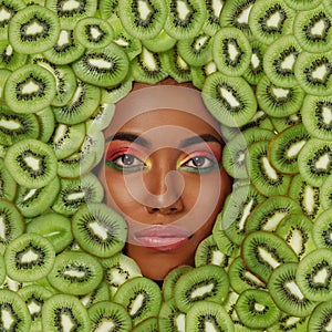 Portrait of a beautiful black woman against the background of sliced kiwi fruit