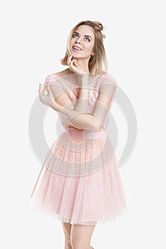 Portrait of beautiful blond dream woman in pink cocktail dress on grey background