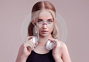 Beautiful blond girl with glamour plasters on her face in white headphones photo