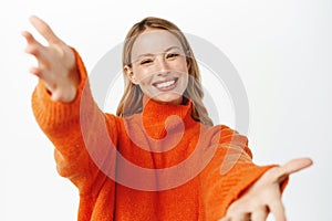 Portrait of beautiful blond girl smiling, reaching hands forward, stretching arms to hold, receive smth, hugging gesture